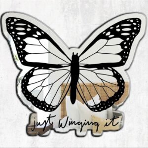 Compact mirror with colorful butterfly design and "Just Winging It" text.