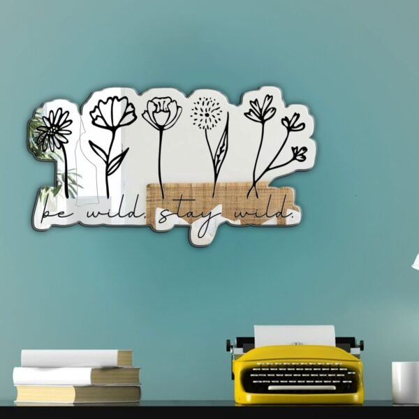 A mirror with a custom-painted design featuring simple flowers and the text "Be wild, stay wild."
