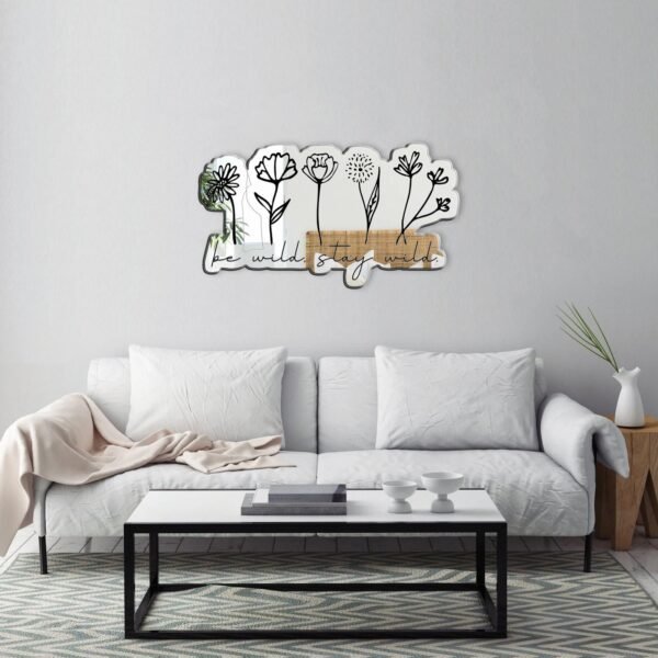 A mirror with a custom-painted design of simple flowers and the phrase "Be wild, stay wild."
