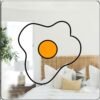 A mirror with an illustration of a fried egg, showing a bright yellow yolk surrounded by white egg whites.
