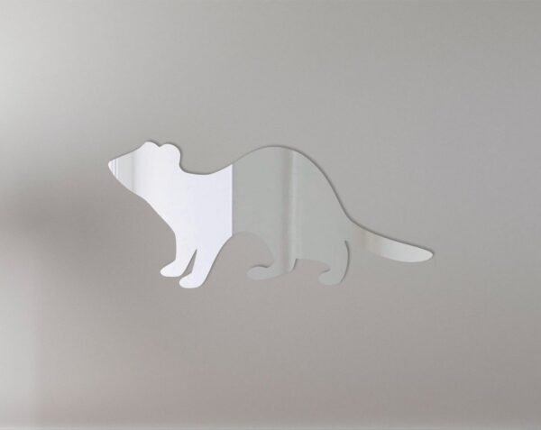 Ferret peering into a round mirror mounted on a sign.