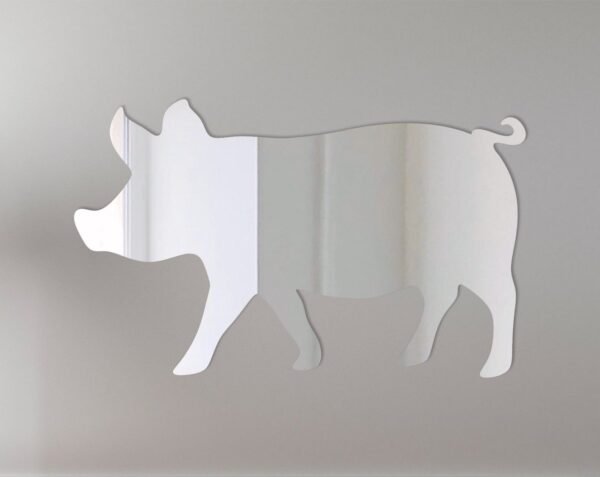 Pink pig-shaped mirror with 'Welcome' sign hanging on a rustic wooden fence.