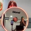 A round mirror featuring the 'Blond' logo and Frank Ocean artwork, surrounded by RGB neon lights in red.