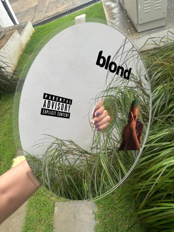 A round mirror displaying the 'Blond' logo and Frank Ocean's artwork, showcased on a modern tabletop